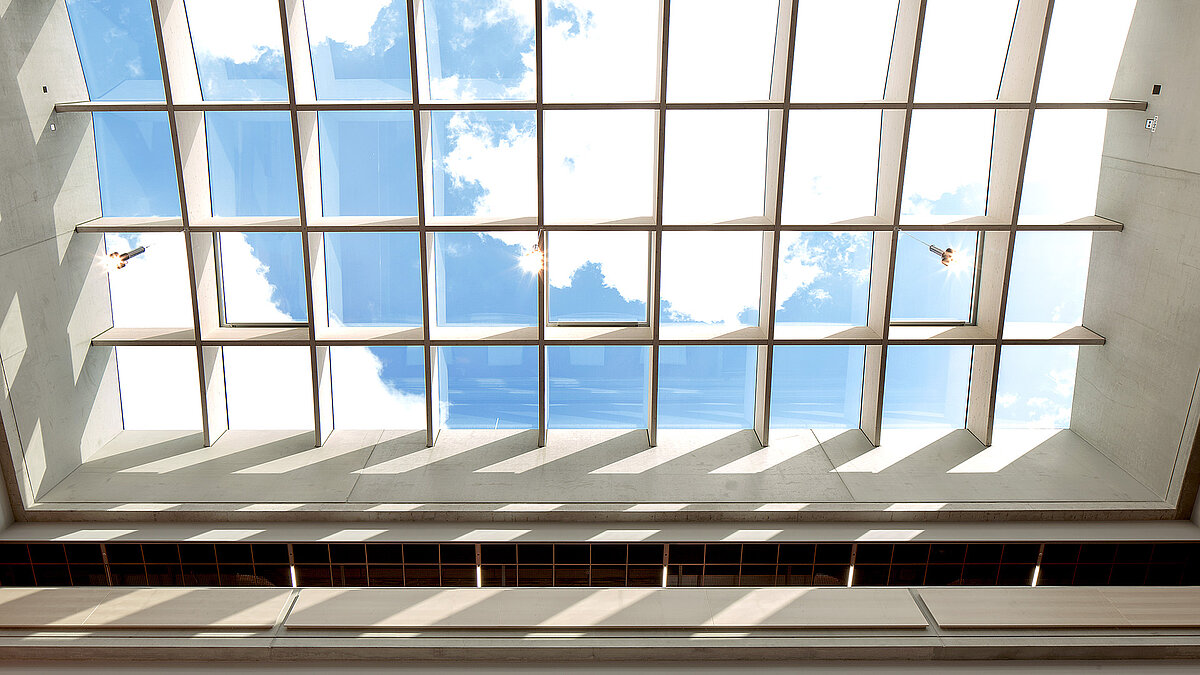 PR60 Passive House glass roof by LAMILUX at Willibald-Gluck-Gymnasium in Neumarkt, showcasing a view of the blue sky and sunlight.