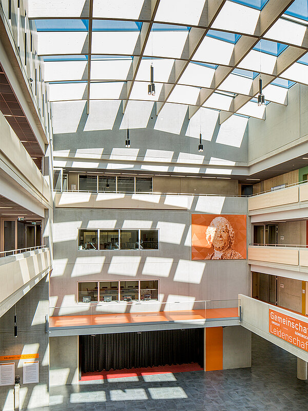 Interior view of the Willibald-Gluck-Gymnasium in Neumarkt with a large LAMILUX glass roof flooding the space with daylight.