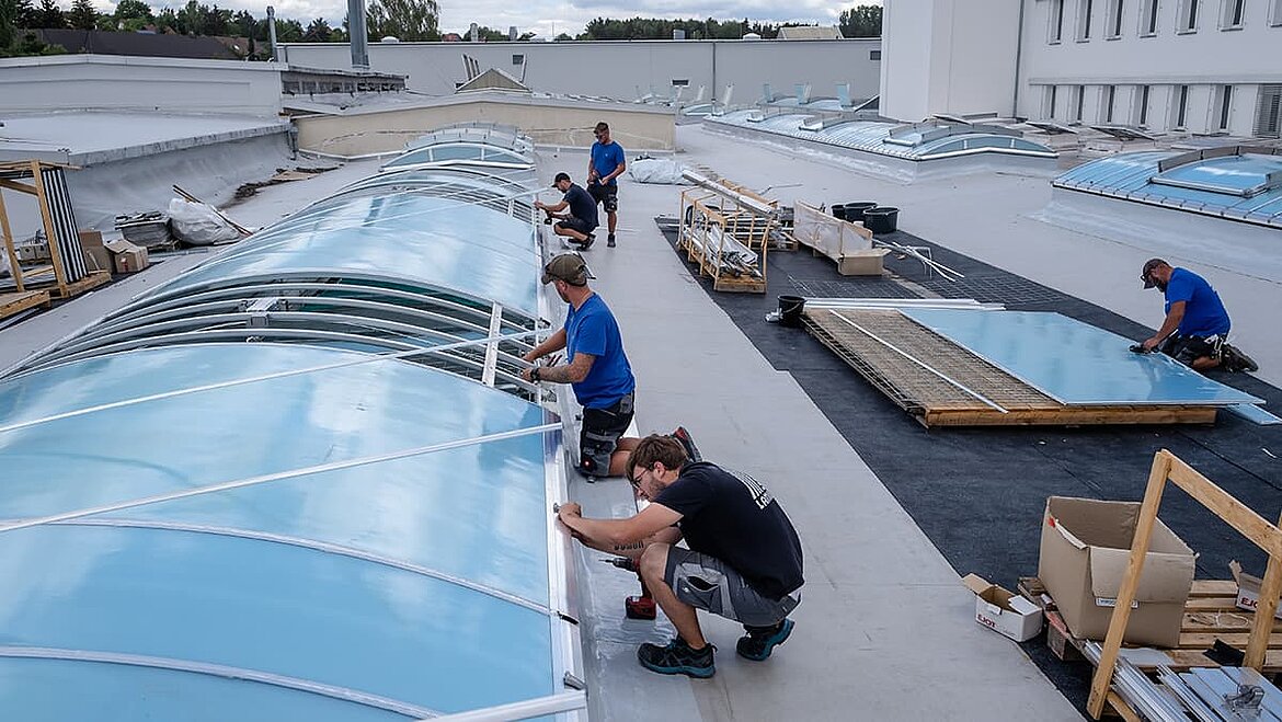 Workers installing skylight strips on a flat roof.