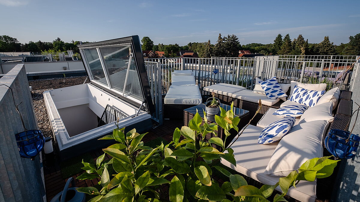 Rooftop terrace of a townhouse in Berlin with flat roof access, seating area, and plants.