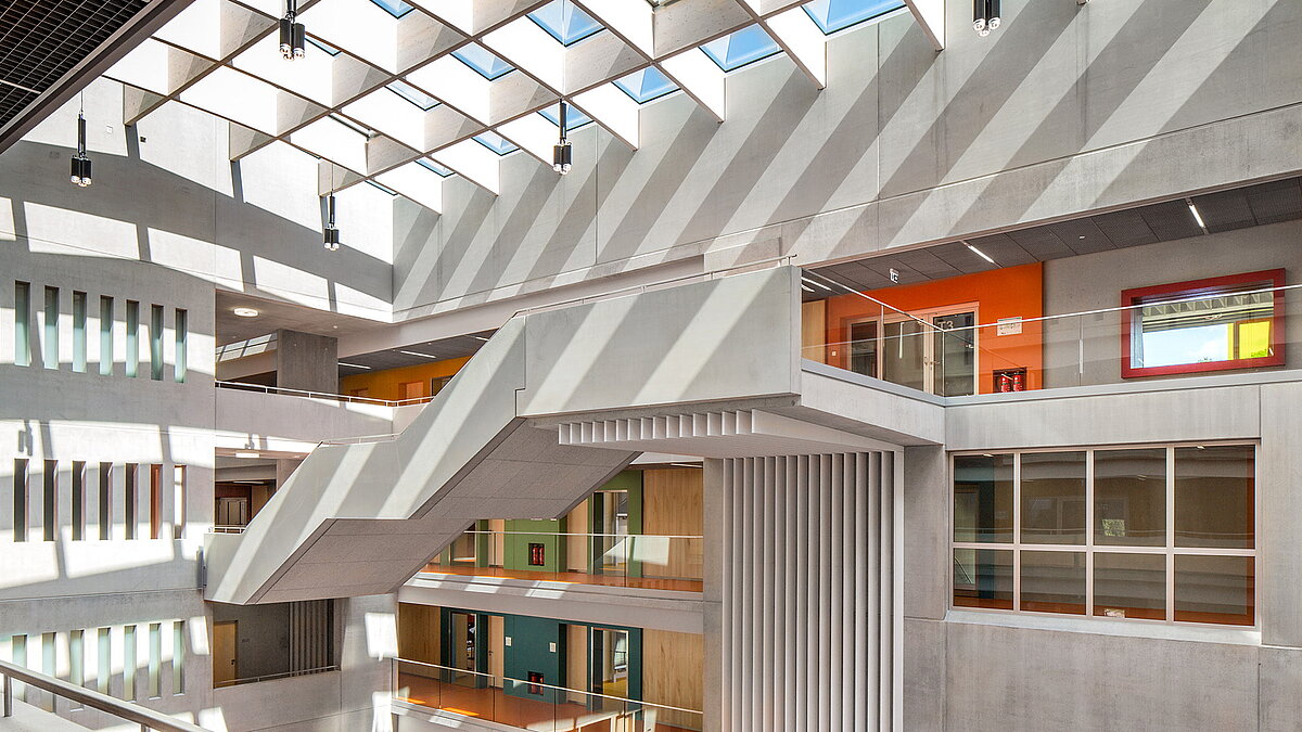 Interior view of Willibald-Gluck-Gymnasium in Neumarkt with LAMILUX glass roofs, modern design, and colorful classrooms.