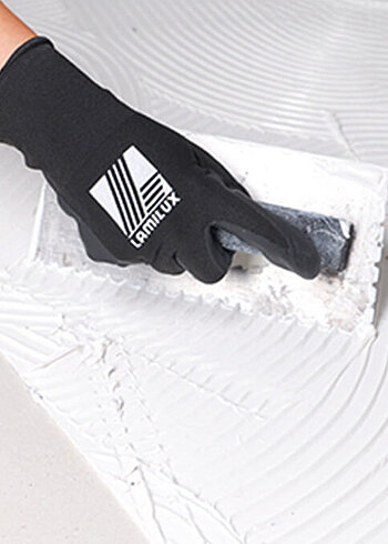 Hand wearing Lamilux gloves smoothing white substance.