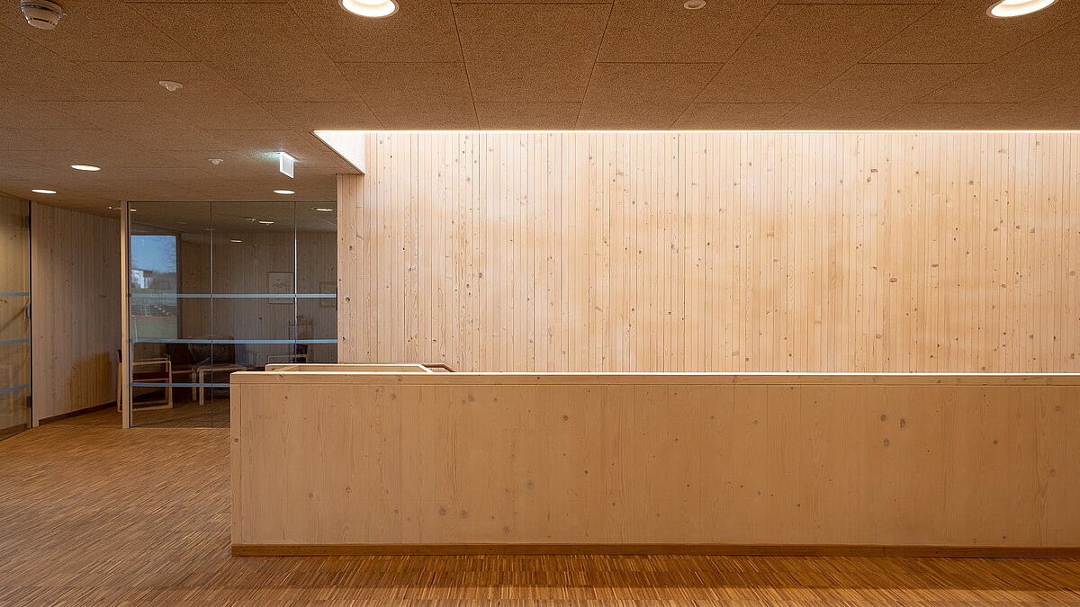 Interior of the Waltenhofen daycare center featuring modern wooden wall design and glass partition.