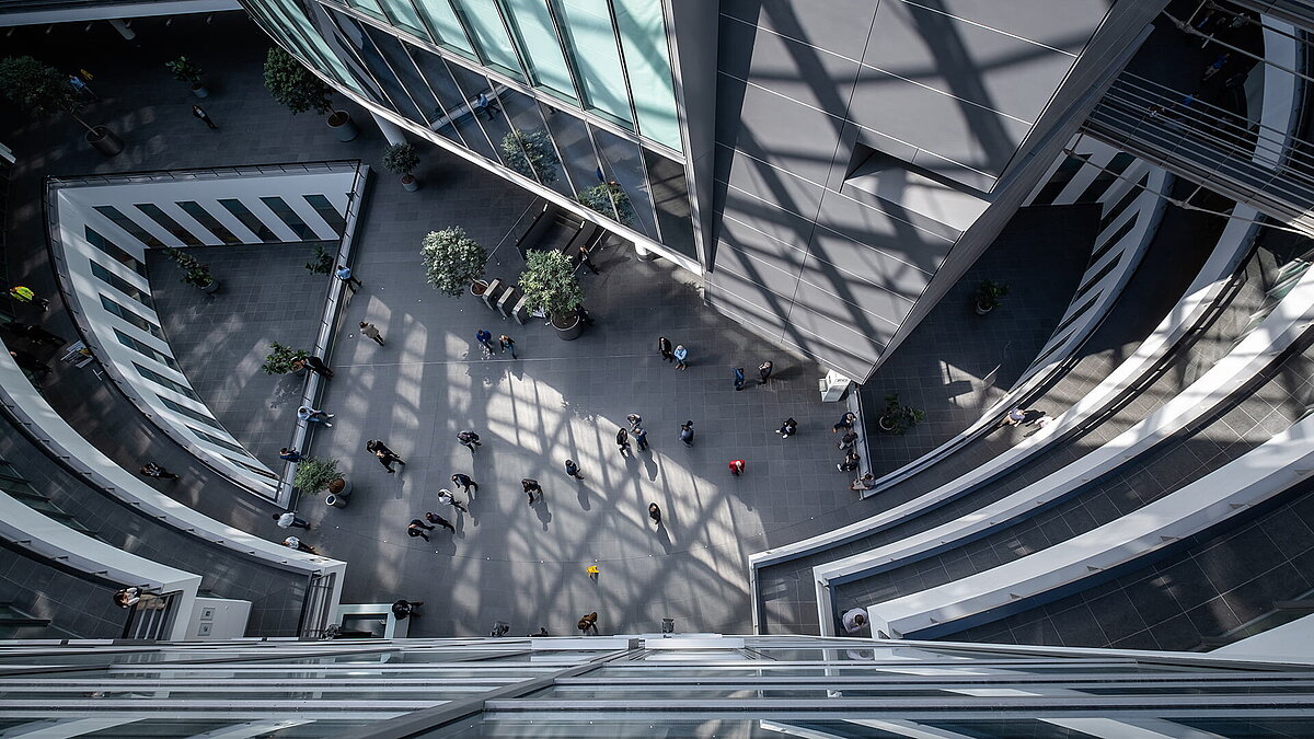 View into the light-filled atrium of the BMW Group Research and Innovation Centre (FIZ) featuring modern architecture and a bustling atmosphere.
