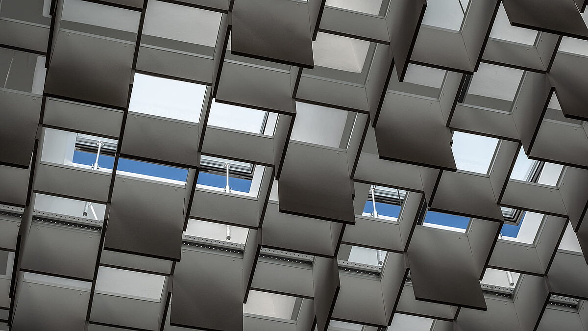 Interior view of the Weiden district court with geometrically arranged ceiling panels and skylights allowing natural light.