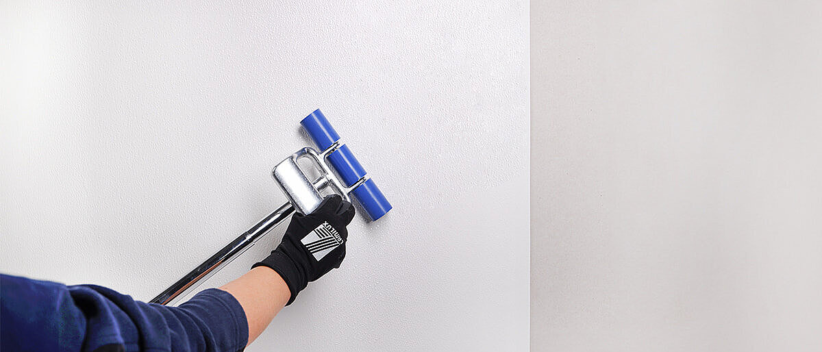 Person using a roller to adhere a white panel to the wall