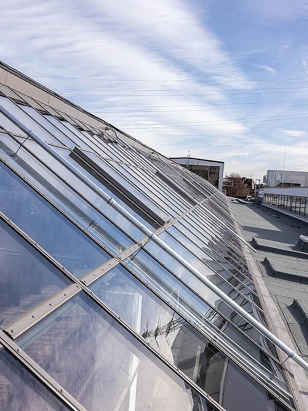 Close-up of the glass roof at Factory Campus Düsseldorf with reflective sky and modern architecture.