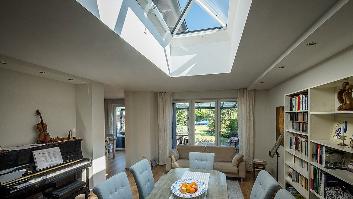 Living room with dining table and large skylight letting in daylight.
