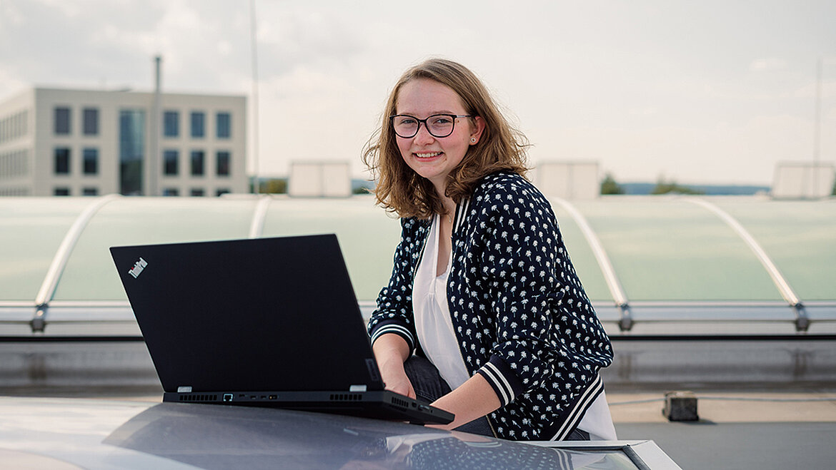 Woman working with a laptop outdoors on a rooftop