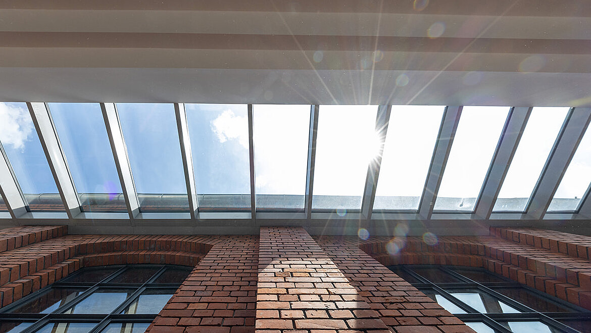Interior with historic brick walls and modern glass roof providing natural daylight