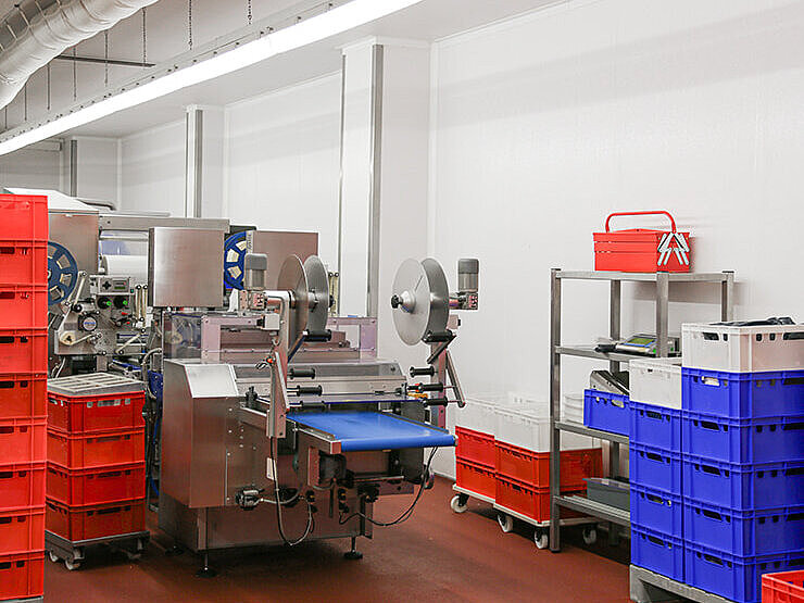 Interior view of a production facility with machines and stacked plastic crates