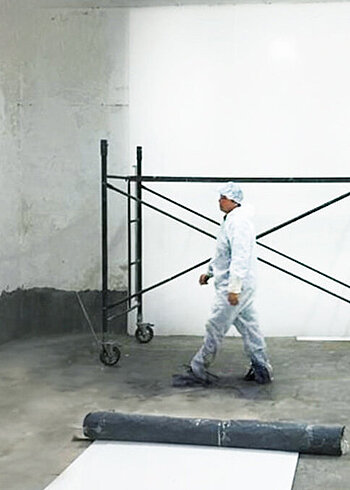 Worker in protective clothing in a room with scaffolding.