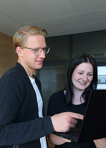 Two people working together on a laptop.