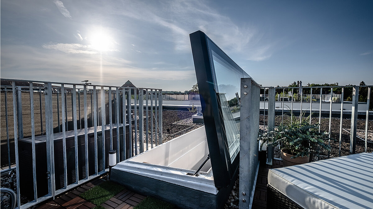 Flat roof exit at a townhouse in Berlin with modern glass cover and railing, sunlight in the background.