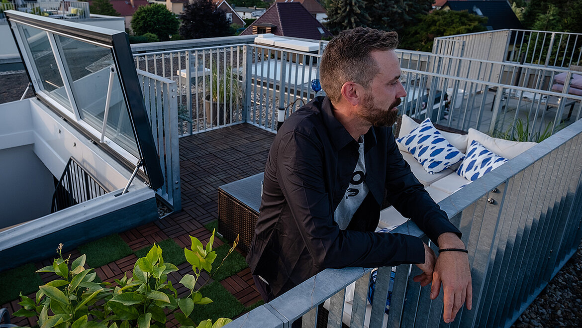Man leaning on a railing on a green flat roof