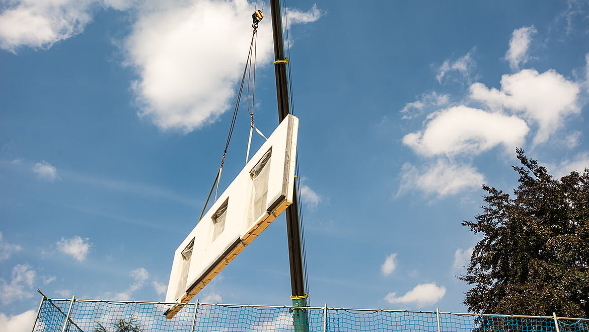 LAMILUX Texture Wall is used as a sandwich wall construction for modular building. Construction site crane holds house wall | insights by LAMILUX