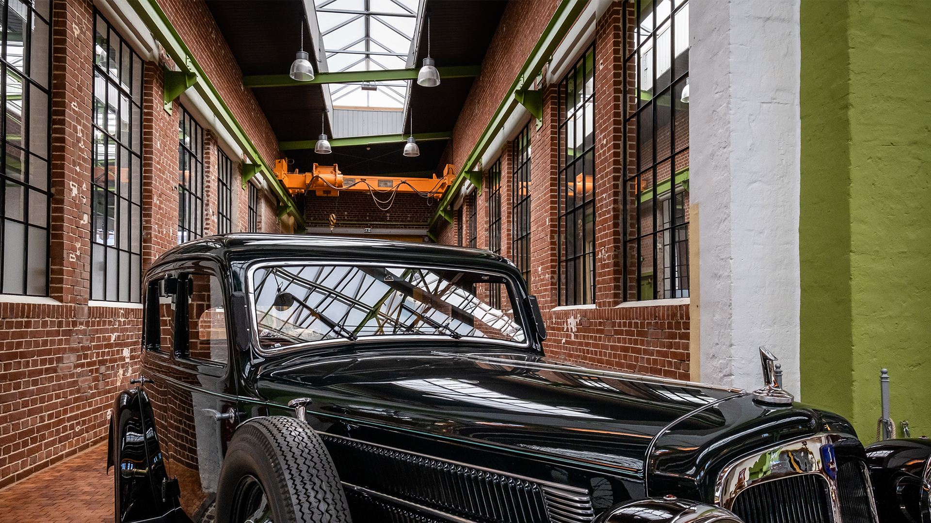 Classic car inside the Zündmagnet event hall in Wurzen with historic brick walls, large glass windows, and skylights.