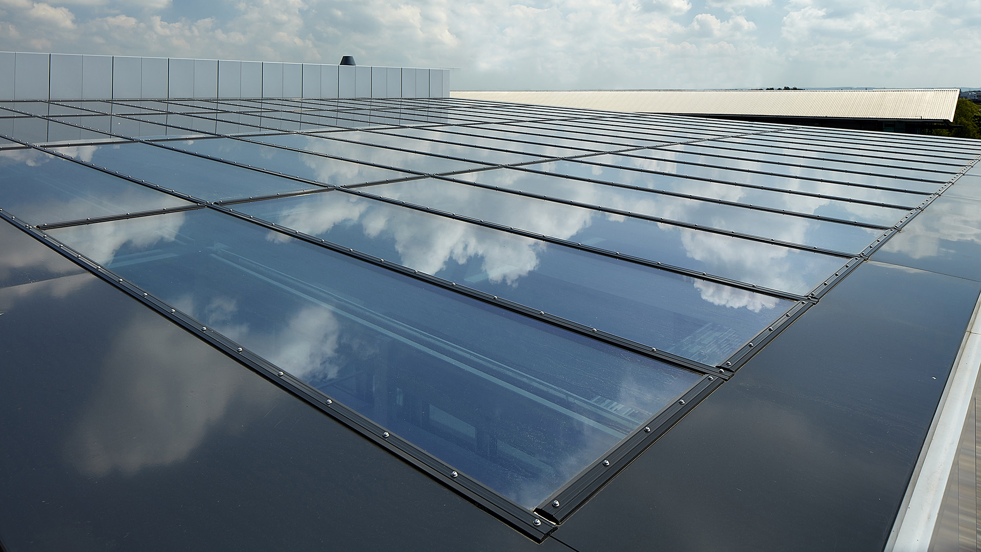 Glass roof of the commercial building in Milton Park, England, reflecting the sky and clouds on its surface.