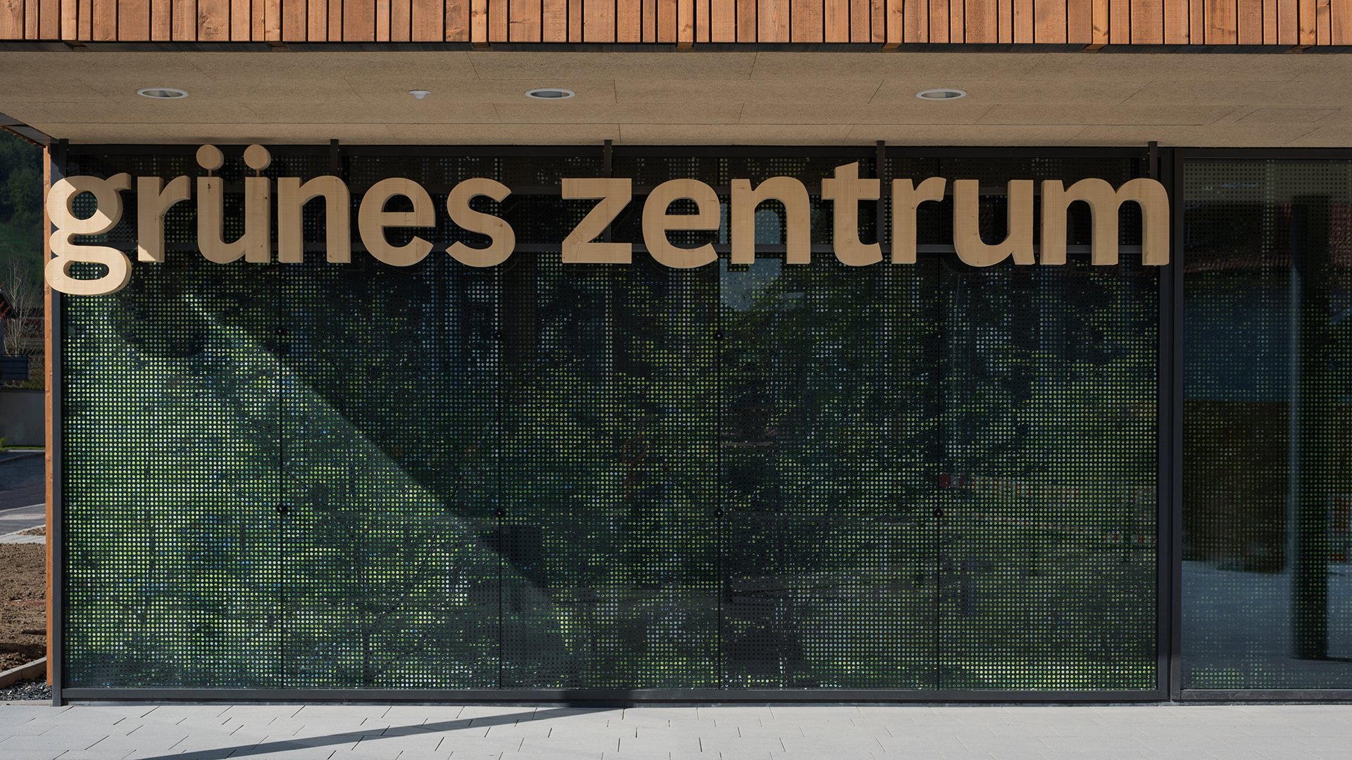 Entrance area of the Green Center Immenstadt with modern glass facade and wooden lettering.