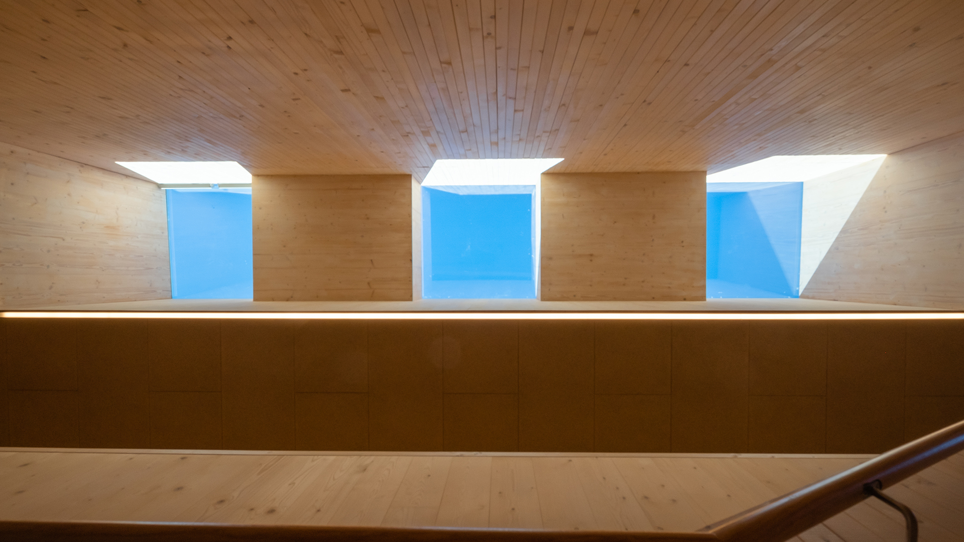 Interior view of the Waltenhofen daycare center featuring rectangular flat roof windows allowing natural daylight through the wooden ceiling.