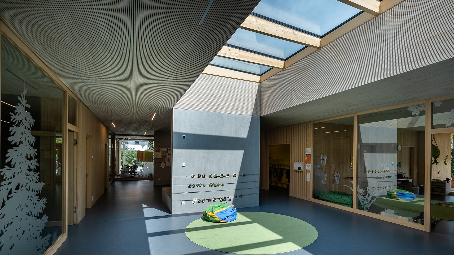 Interior of the Wiggensbach daycare center with large glass roofs providing natural light to the modern, light-filled space.