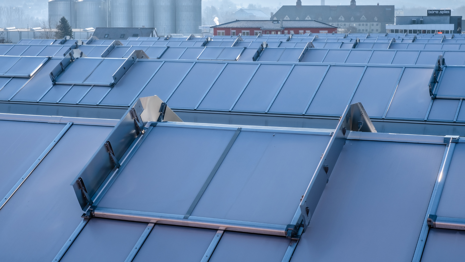 Roof of the OBI hardware store in Bamberg featuring modern skylight panels for natural lighting, with silos and industrial buildings in the background.