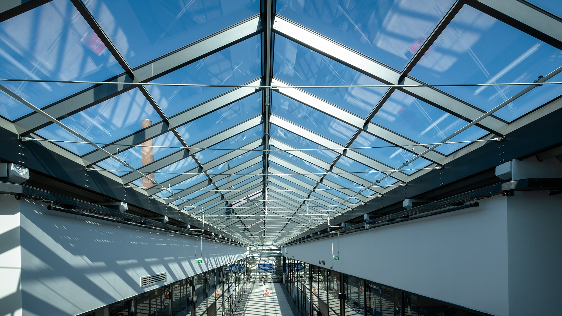 Interior view of the LAMILUX glass roof PR60 in the Outlet Centre Selb with blue sky.