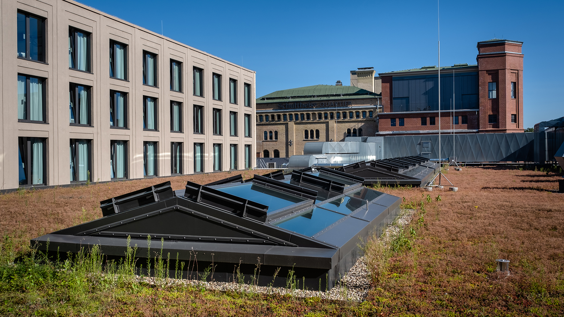 Green roof of the Schultheiss Quartier in Berlin-Moabit with glass roofs and a modern building complex in the background.