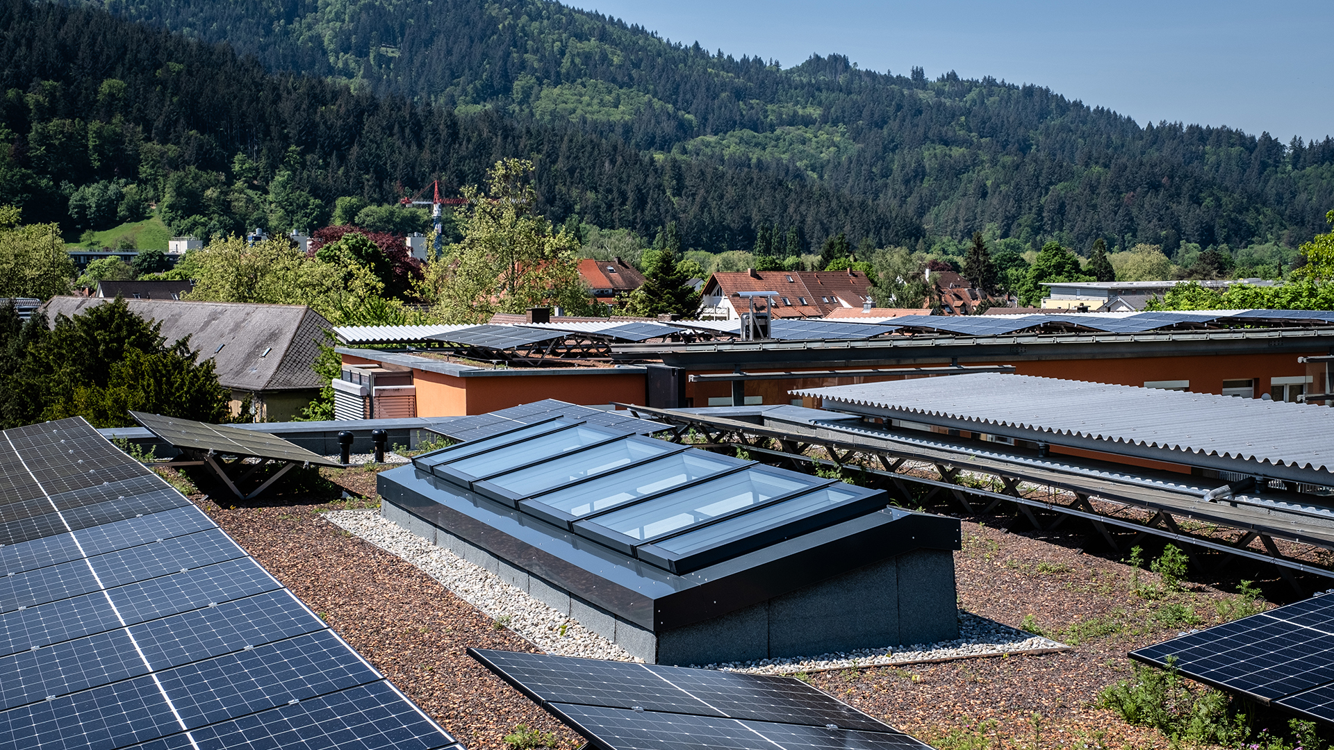 Modular glass roof from LAMILUX on a residential building in Freiburg, surrounded by solar panels and a green landscape.